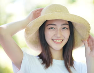 麦わら帽子を被り、白いTシャツを着た若い女性