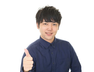 紺色のシャツを着た若い男性がグーのサインをしている様子