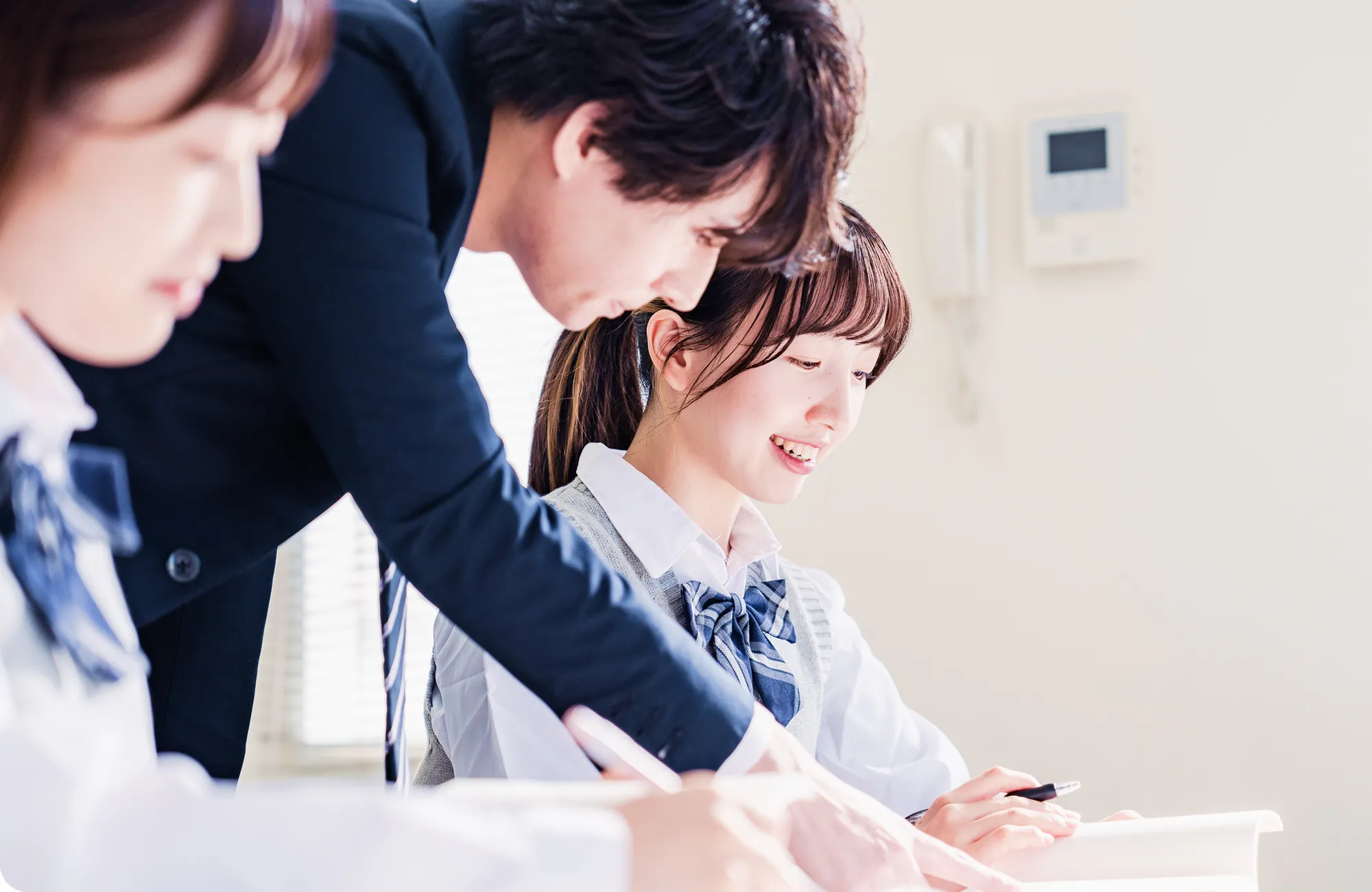 講師が机の上で丁寧に指導し、生徒が真剣に聞いている様子