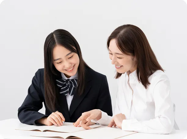 生徒のノートを一緒に確認し、優しく指導する女性講師