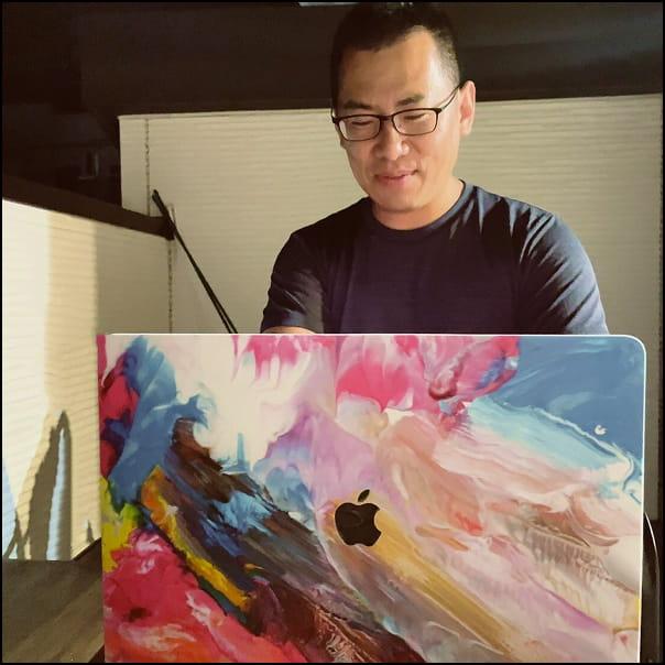 屋上で夜空の下、パソコンの前に座って作業をしている男性（本人）